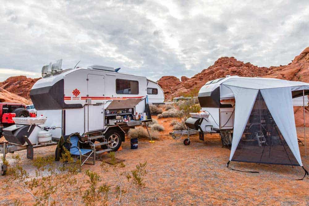 A group of campers in the desert with tents.