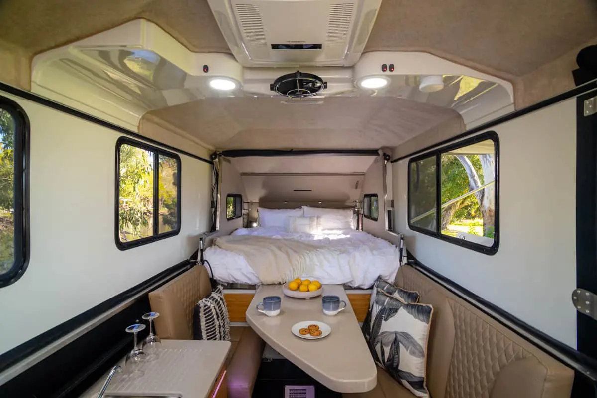 A bed and table in the back of an rv.