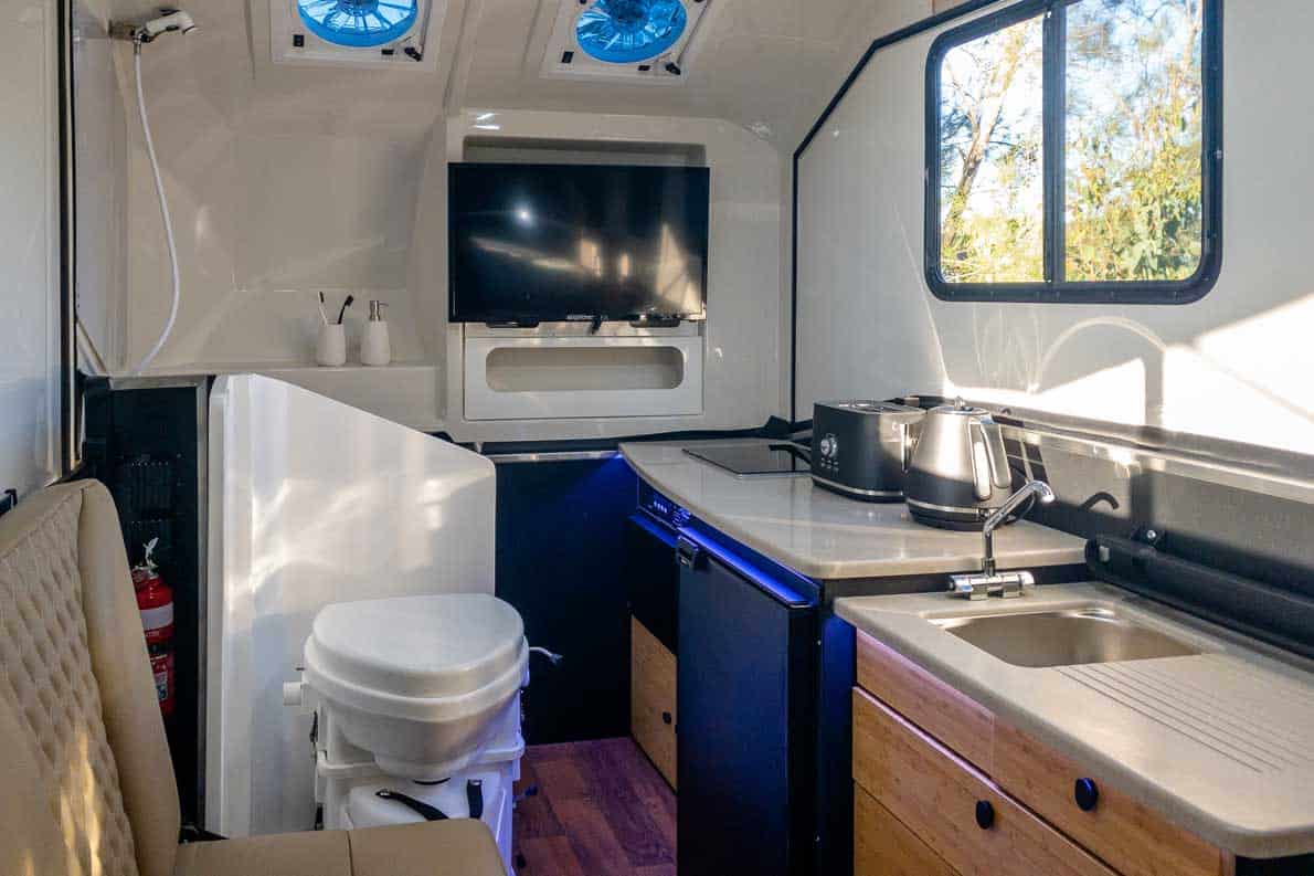 A kitchen with a sink, toilet and television.