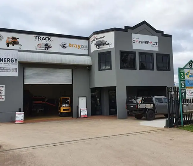 A building with two cars parked in front of it.