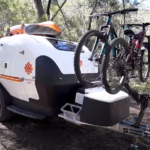 A bicycle rack attached to the back of an ambulance trailer.