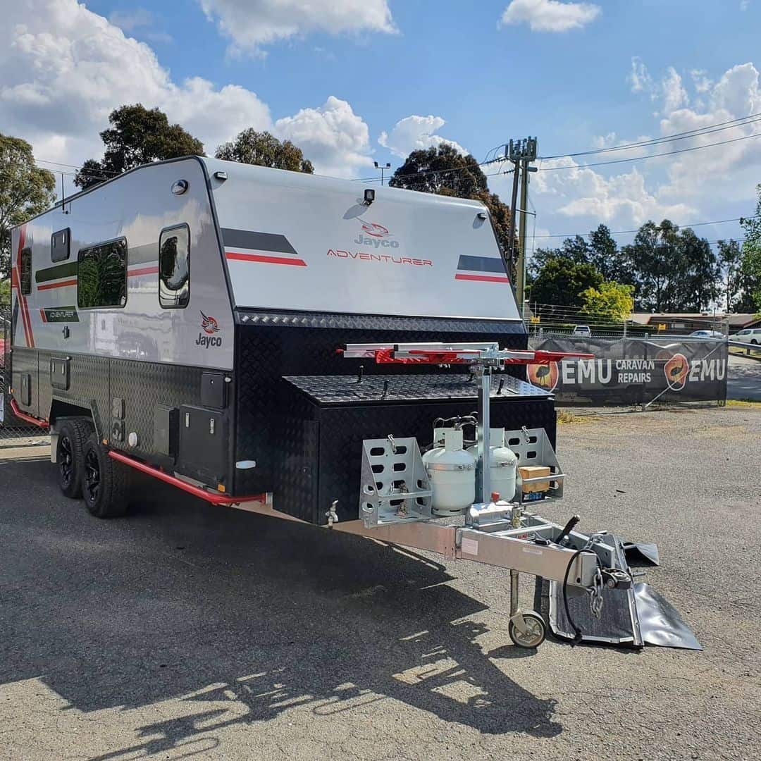 A white trailer with a large black and red trailer on it's back.