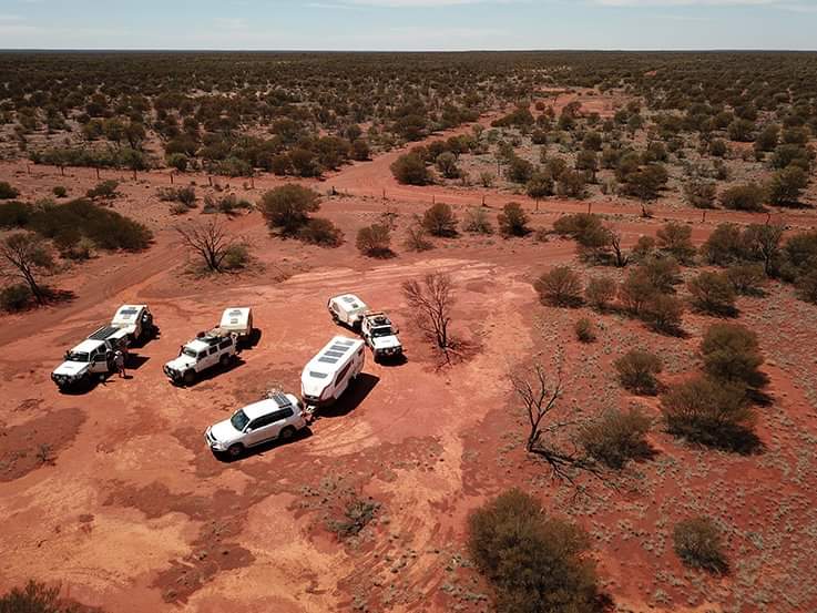 A group of vehicles parked in the middle of an arid area.