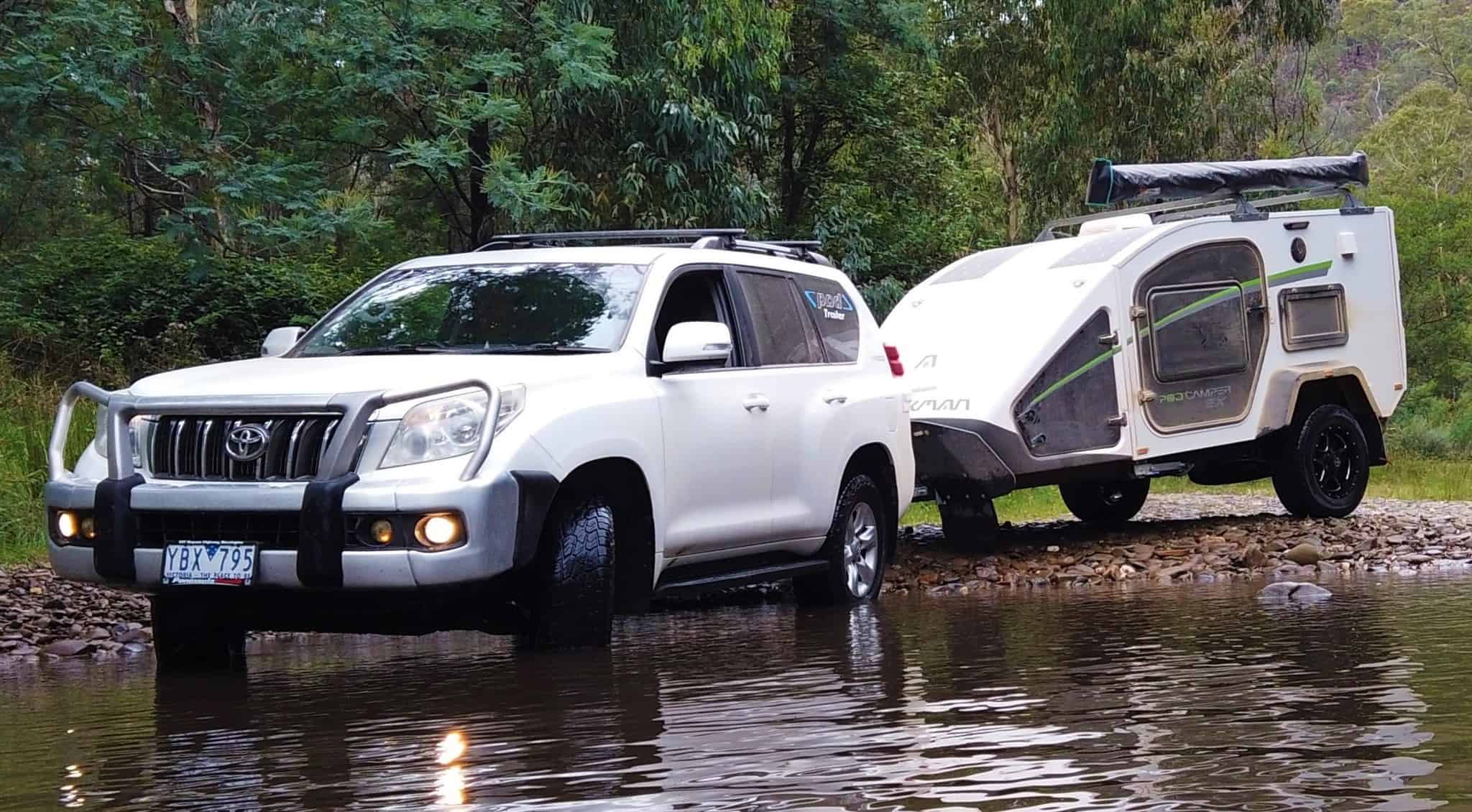 A white suv and trailer are in the water.