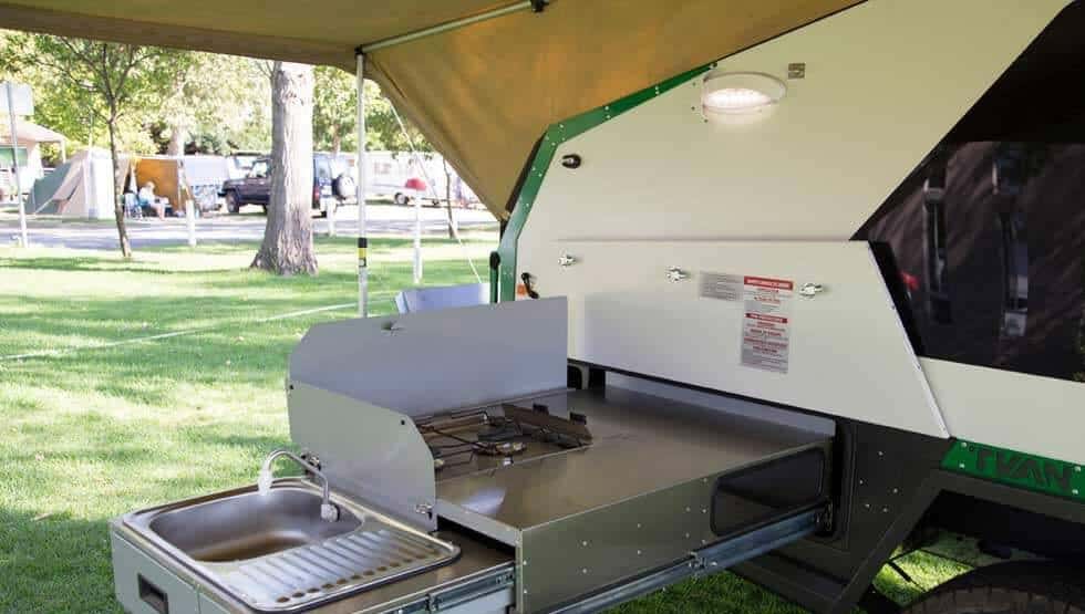 A small trailer with an oven and sink in it.