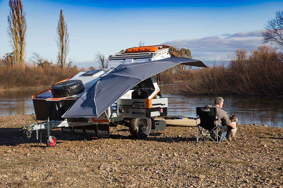 A man sitting on the back of a truck with an umbrella over it.