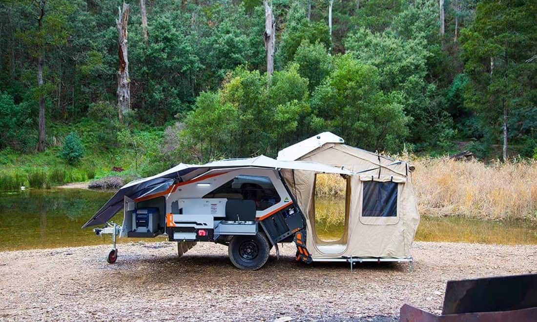 A camper trailer with a tent on the back.