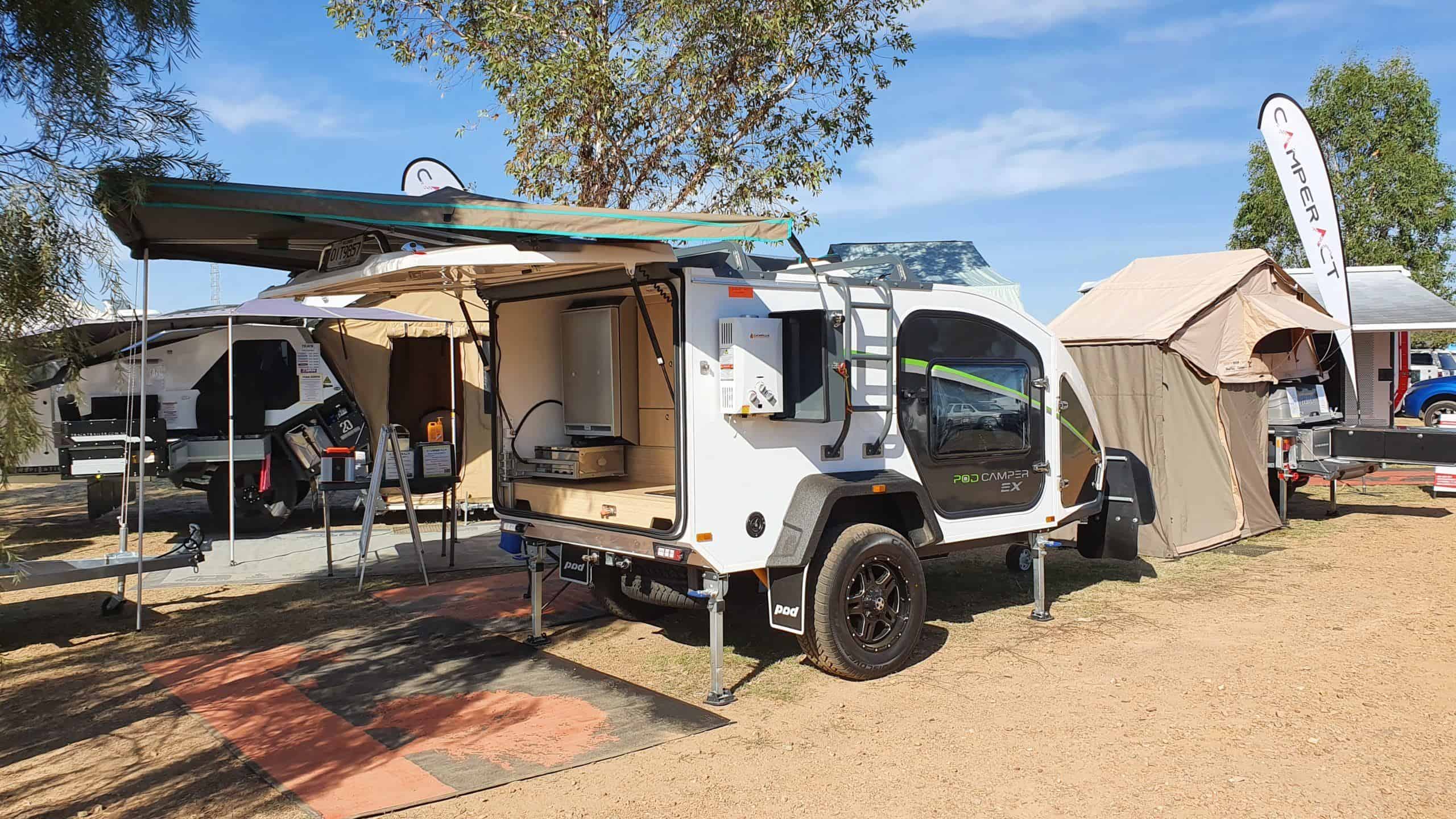 A small camper trailer with an awning and a ladder.