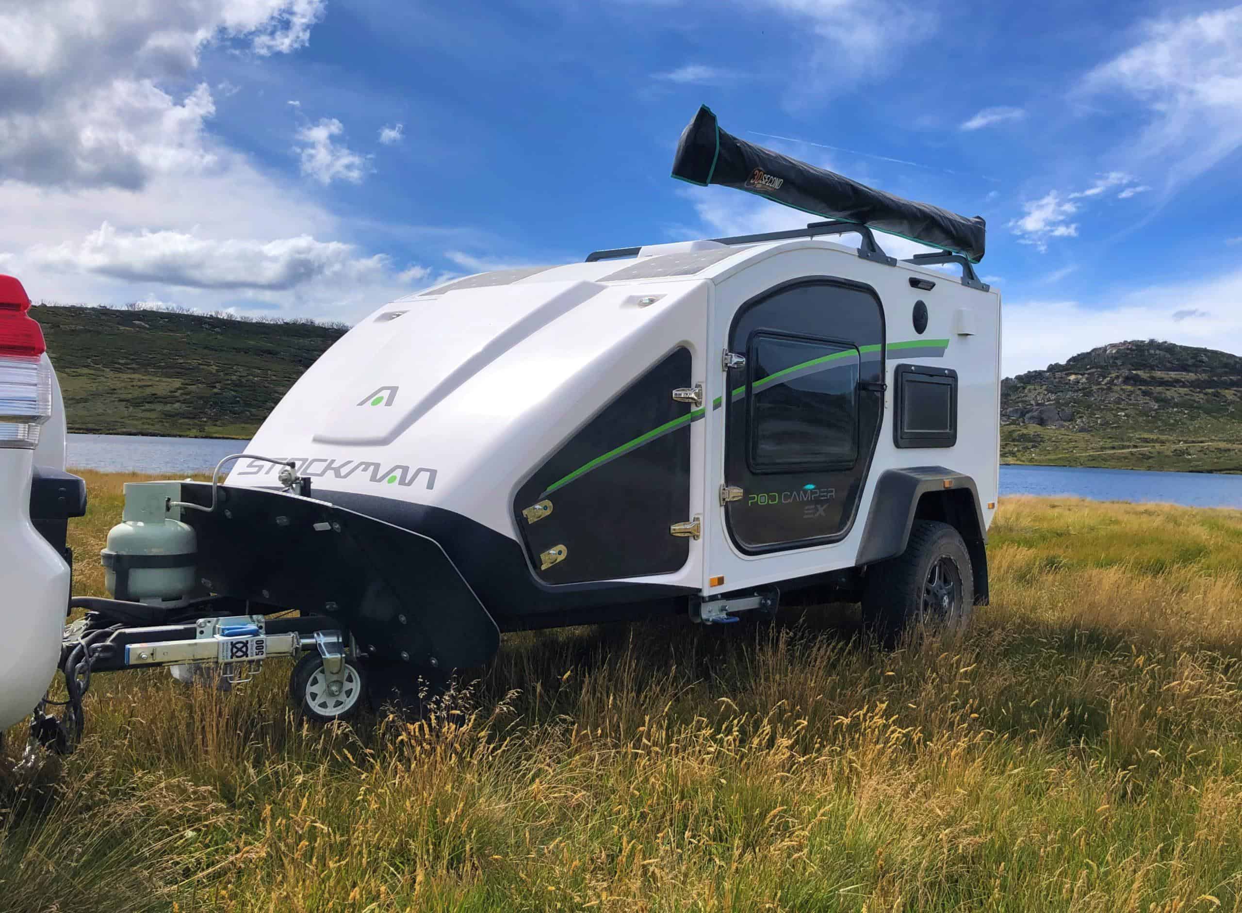 A white trailer with a black and green trim parked in the grass.