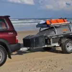 A red suv pulling a trailer with luggage on it.