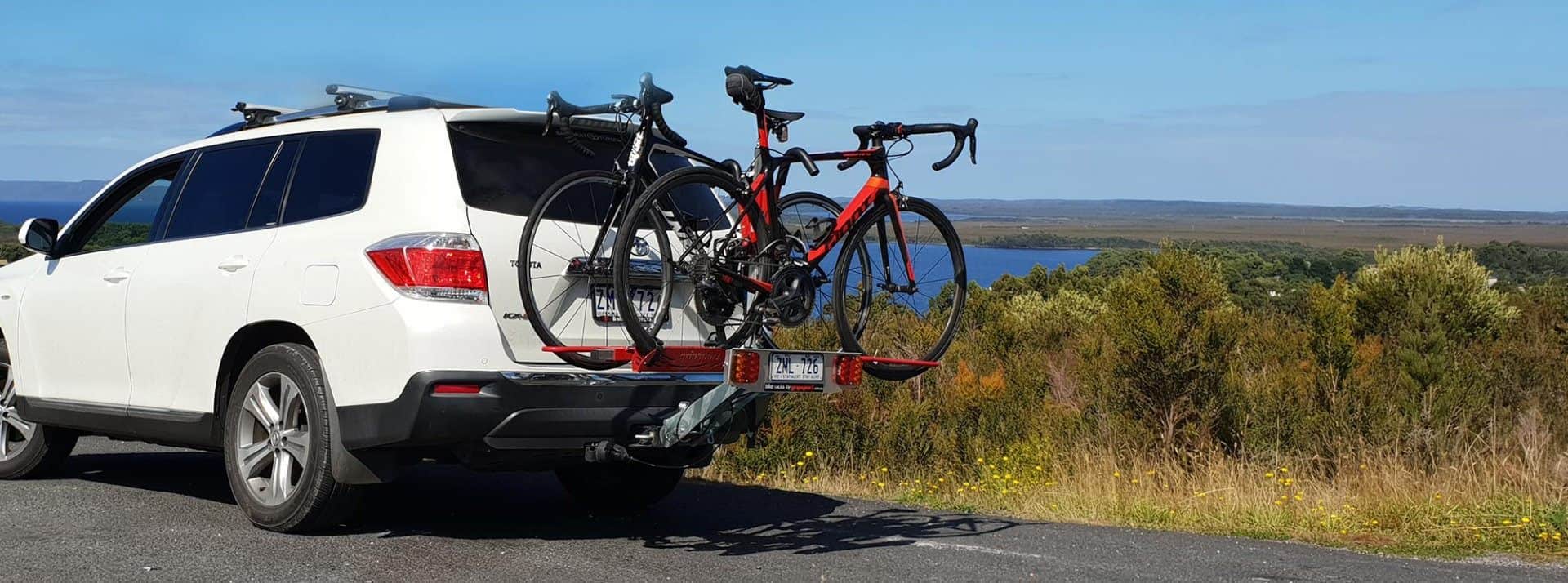 A bicycle is strapped to the back of a truck.