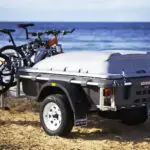 A trailer with two bikes on it parked in the sand.