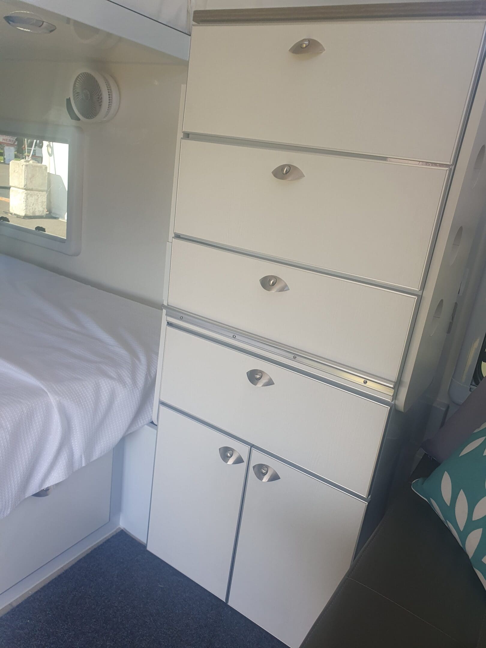 A white cabinet with drawers and a mirror above it.